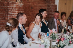 This picture shows the top table during the wedding breakfast. The top table is set up in front of the red brock wall.