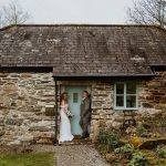 Couple standing outside a wedding cottage in Cornwall