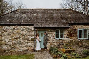 Couple standing outside a wedding cottage in Cornwall